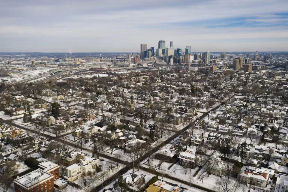 Aerial view of Minneapolis neighborhood and downtown skyline in winter with snow.